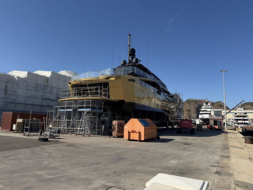 Stern view of the yacht in a maintenance yard with scaffolding.